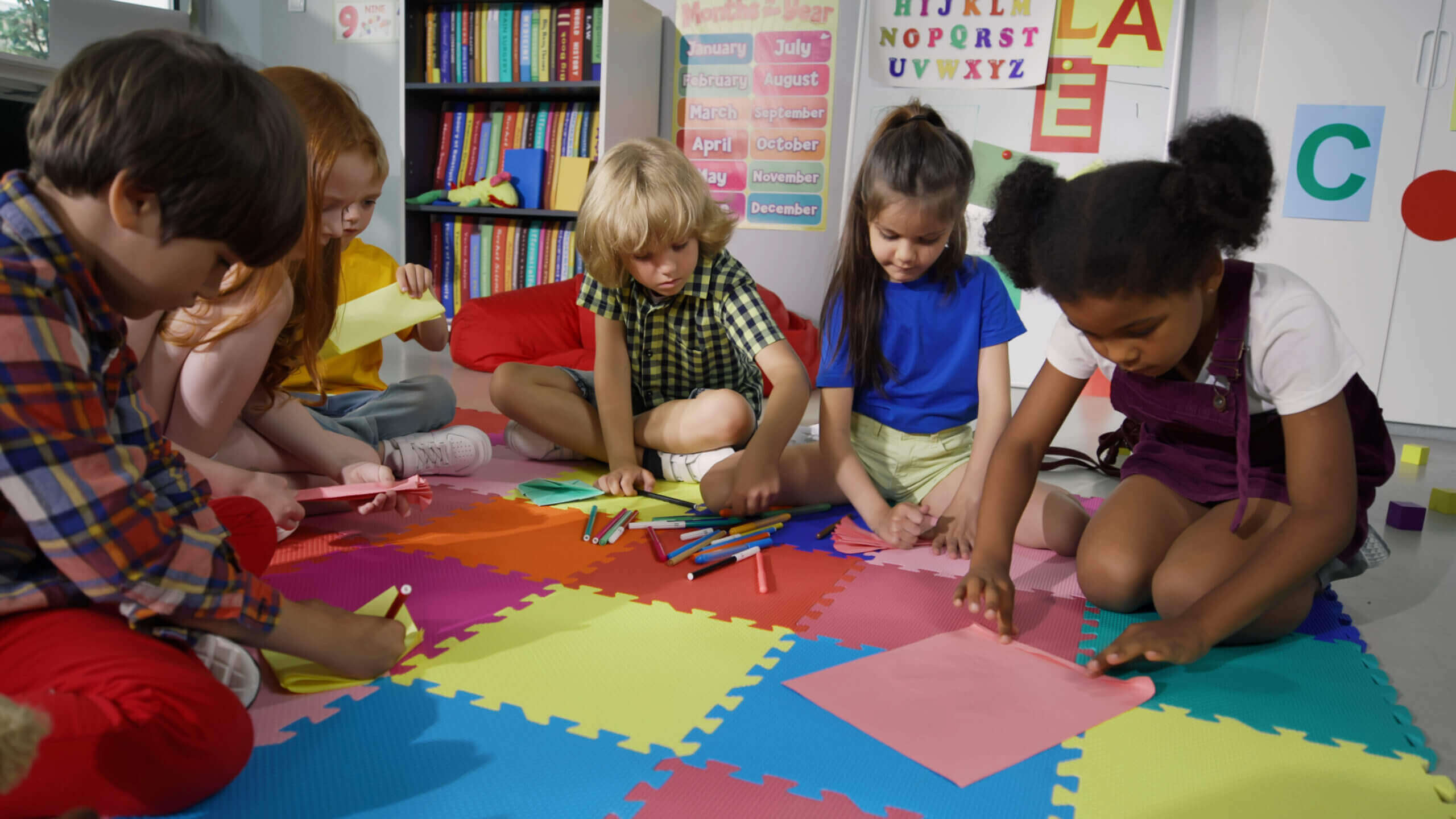 Children drawing on colorful foam mat.